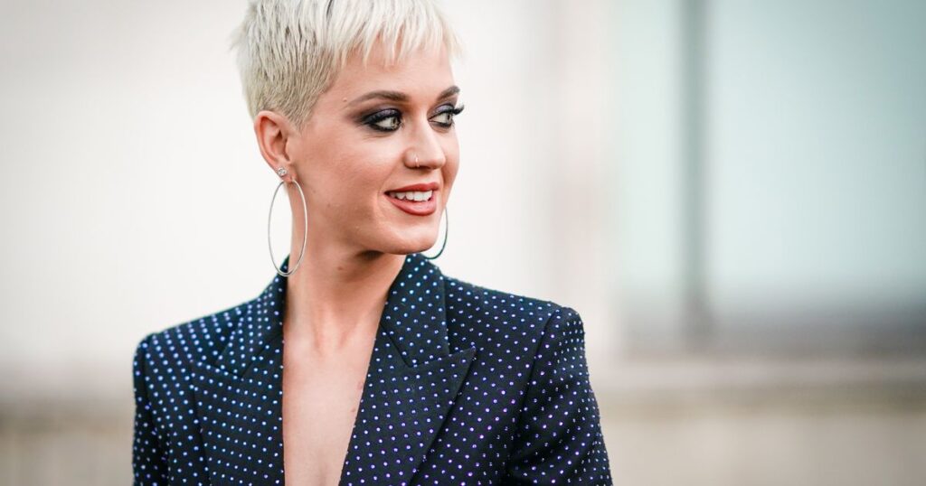 A woman with short blonde hair in a polka dot suit, showcasing a perfectly trendy long pixie cut.