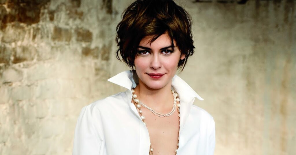 A woman in a white shirt adorned with pearls, showcasing her elegant style and short wavy layers hairstyle.