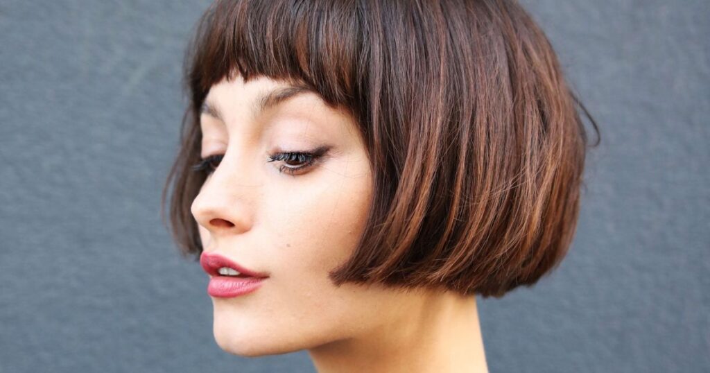 A woman showcasing a stylish wavy bob with full bangs, highlighting her modern and chic hairstyle.